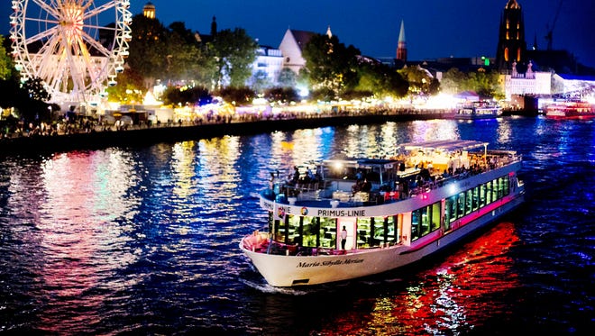 Un barco de fiesta pasa una rueda de la fortuna en el r í o Main durante la fiesta de Mainfest en Frankfurt, Alemania, el s á bado 4 de agosto de 2018.