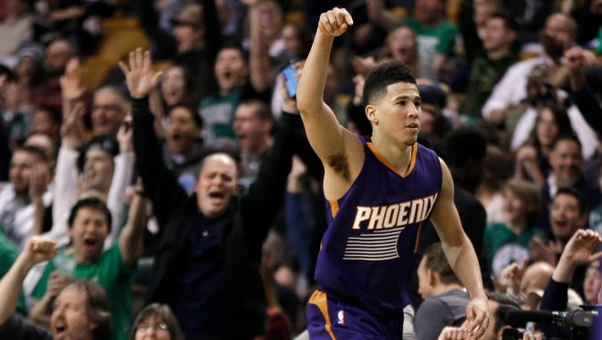 Phoenix Suns guard Devin Booker gestures after he scored a basket, as fans cheer him at TD Garden in the fourth quarter of the Suns' NBA basketball game against the Boston Celtics, Friday, March 24, 2017, in Boston. Booker scored 70 points, but the Celtics wonp 130-120. Booker is just the sixth player in NBA history to score 70 or more points in a game.