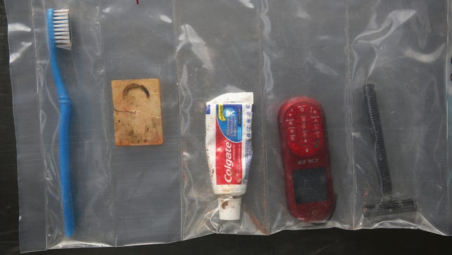 Un cepillo de dientes, pasta, una fotografía tamaño cartera, un celular nokia y un rastrillo.