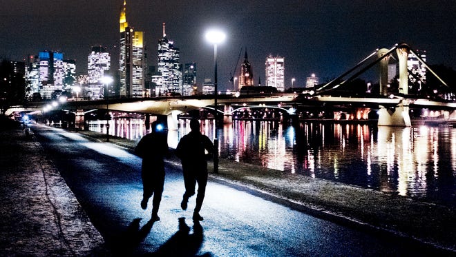Dos hombres corren a lo largo del r í o Main con los edificios del distrito bancario al fondo en Frankfurt, Alemania, el martes 22 de enero de 2019.
