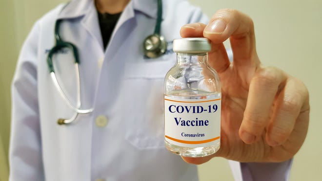 Doctor holding glass vial labeled COVID-19 vaccine coronavirus.