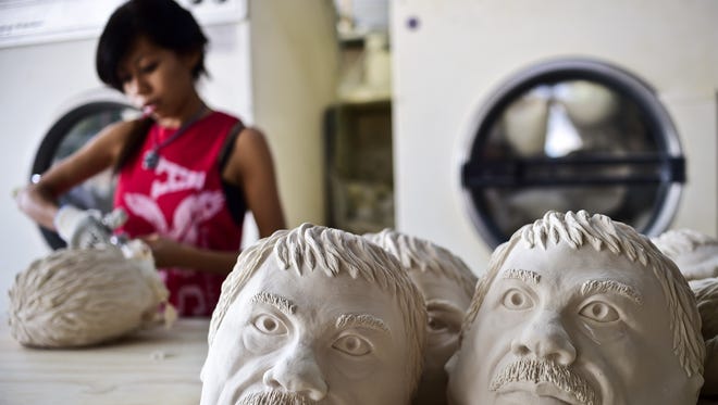 Una mujer trabaja en una fábrica de máscaras. En primer plano se muestran los moldes que utilizan para darle forma al rostro del capo de las drogas Joaquin "Chapo" Guzmán.