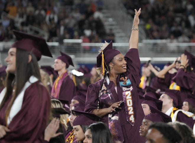 A student waves toward the crowd during Arizona State University's commencement ceremony in Tempe.