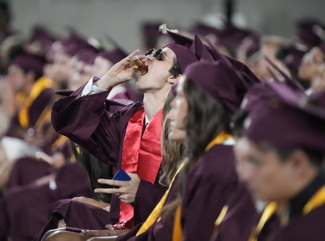 A student drinks a beverage during Arizona State University's commencement ceremony in Tempe.