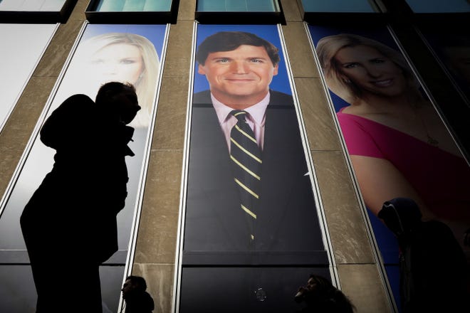 People pass by a promo of Fox News host Tucker Carlson on the News Corporation building in New York, March 13, 2019.
