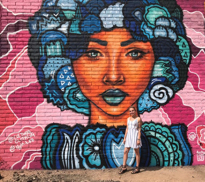 La artista callejera Nyla Lee se encuentra junto a un mural que pint ó en la Calle 7, en Phoenix.