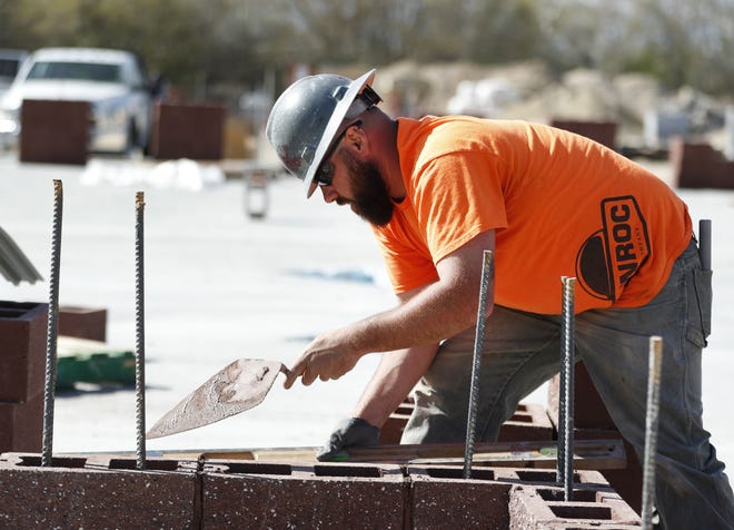 Un trabajador de construcción pone cemento en unos ladrillos durante la construcción de una nueva escuela.