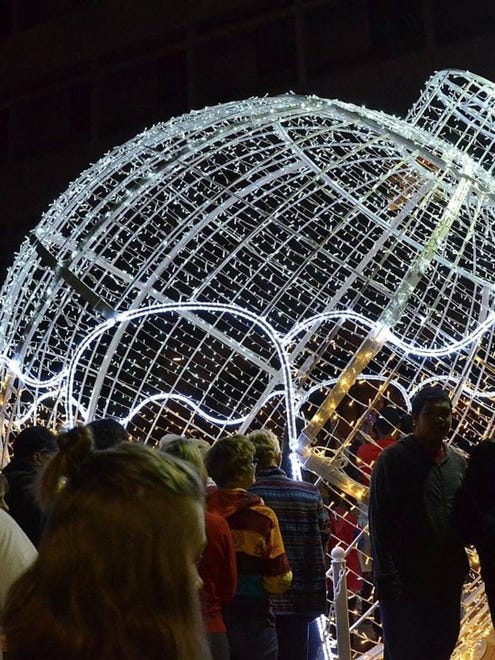 Los visitantes caminan a través de un adorno festivo gigante el viernes 25 de noviembre de 2016 cuando Glendale Glitters inició su festival anual de luces, conciertos y compras después del anochecer.