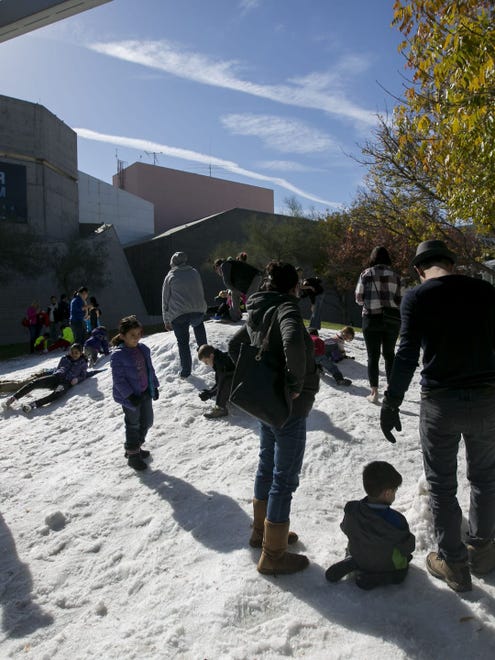 Las familias juegan en la nieve en el Centro de Ciencias de Arizona en Phoenix.