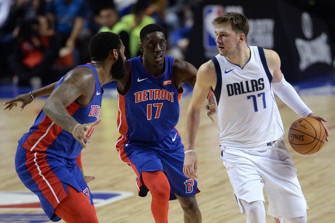 Dallas Mavericks forward Luka Doncic dribbles while defended by Detroit Pistons forward Tony Snell (17) and center Andre Drummond during the second half Dec. 12, 2019.