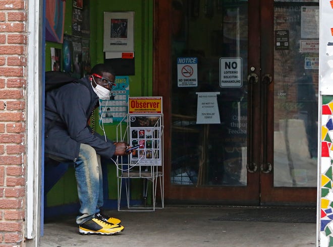 Un hombre que llevaba una máscara se sienta en la entrada de un restaurante cerrado, en Dallas, Texas, EE.UU.