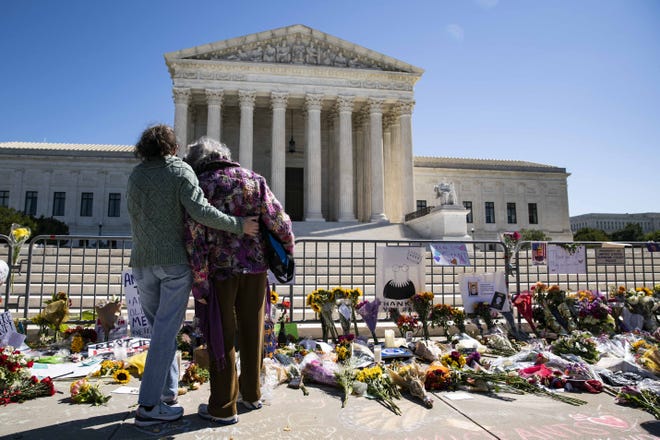 Dos personas lamentan la muerte de la jueza Ruth Bader Ginsburg frente a la Corte Suprema de EEUU.