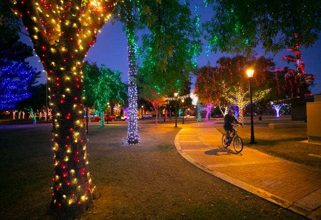 A man rides his bike through the holiday lights of Glendale Glitters at Murphy Park in downtown Glendale on Nov. 23, 2020.