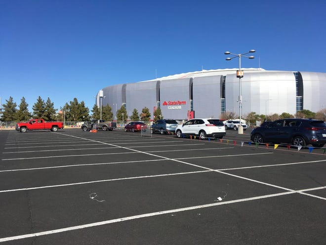 Los conductores esperan en la fila para recibir la vacuna COVID-19 en el estacionamiento del State Farm Stadium en Glendale, Arizona, el lunes 11 de enero de 2021. El estadio de los Arizona Cardinals abrió como un sitio de vacunación el lunes que operará 24/7.