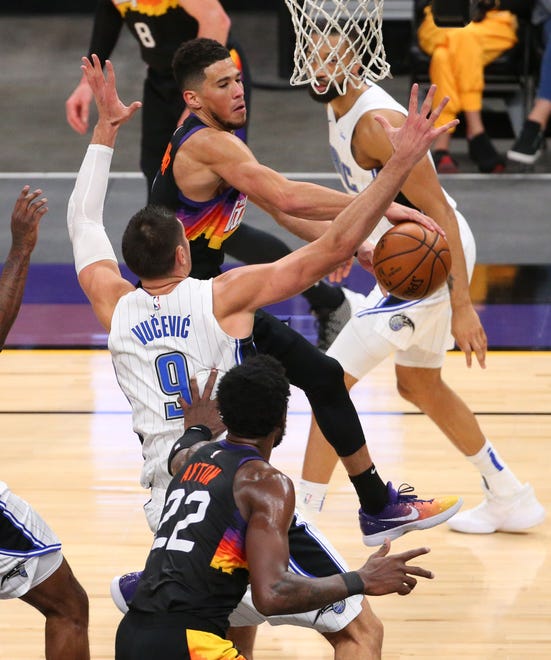 Phoenix Suns guard Devin Booker (1) passes the ball off to center Deandre Ayton (22) against Orlando Magic center Nikola Vucevic (9) during the third quarter Feb. 14, 2021.