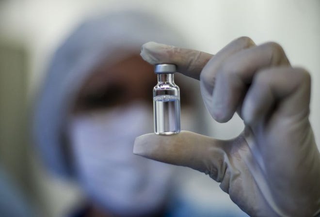Una trabajadora muestra un vial de la vacuna contra el coronavirus desarrollada por AstraZeneca y la Universidad de Oxford, y producida por la Fundación Fiocruz en Río de Janeiro, Brasil, el 12 de febrero de 2021.