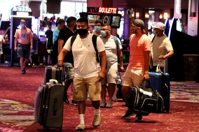 Los visitantes hacen rodar sus maletas hacia sus habitaciones en el Mirage el 27 de agosto de 2020.