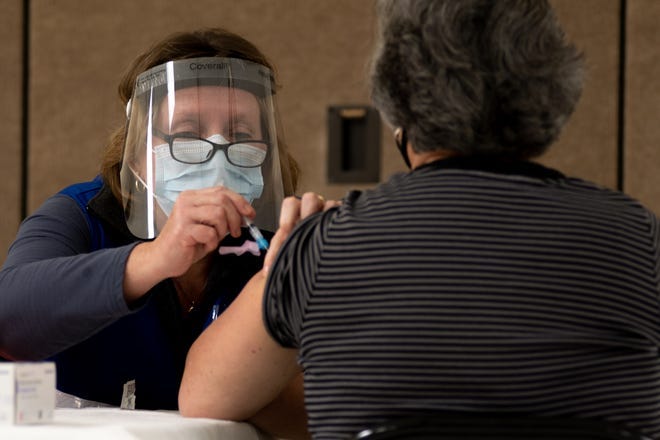 Una profesional de la salud aplica una vacuna a una mujer mayor a 65 años.